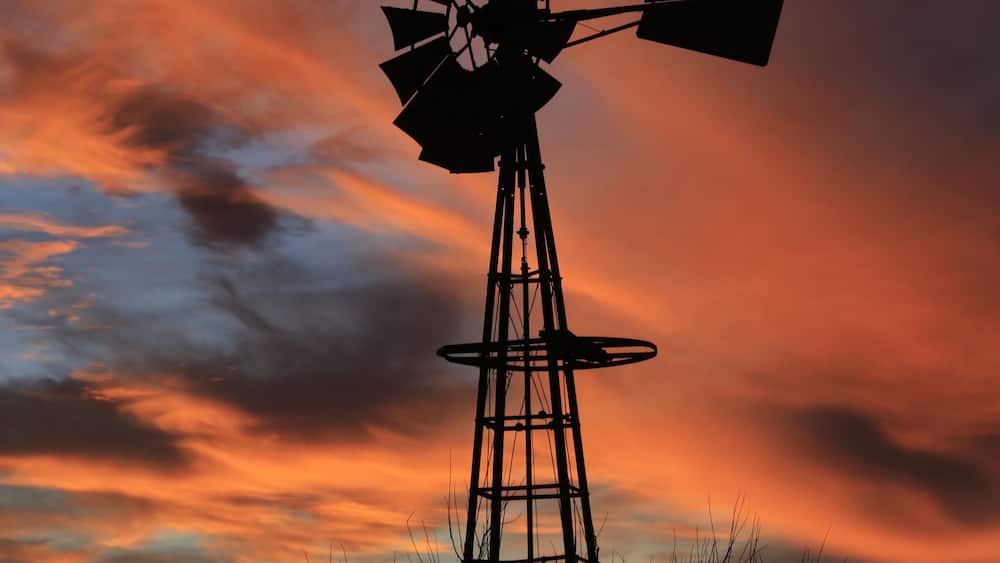 La silhouette dâun moulin Ă vent se dĂ©tachant sur le ciel au coucher du soleil.