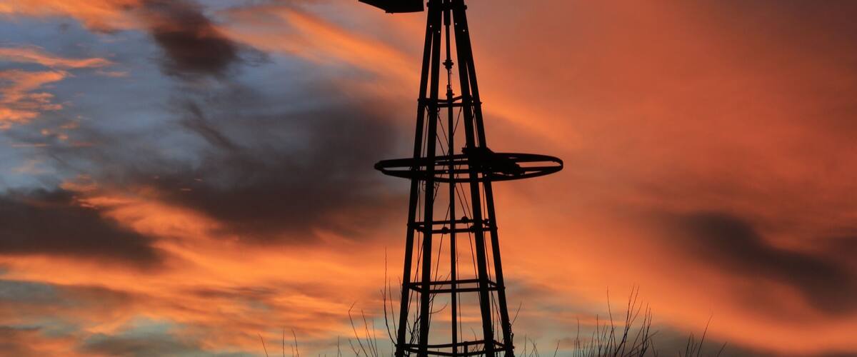 A windmill silhouette against a sunset sky.