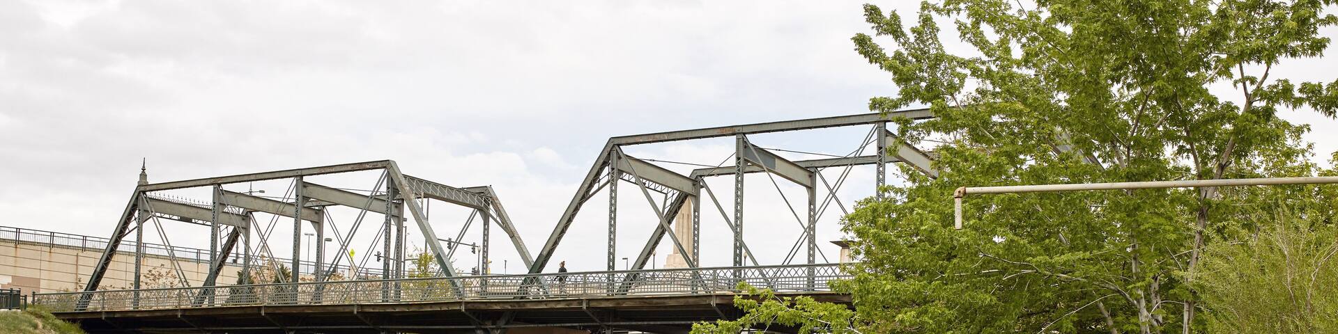 Un puente de acero sobre un río, rodeado de vegetación.