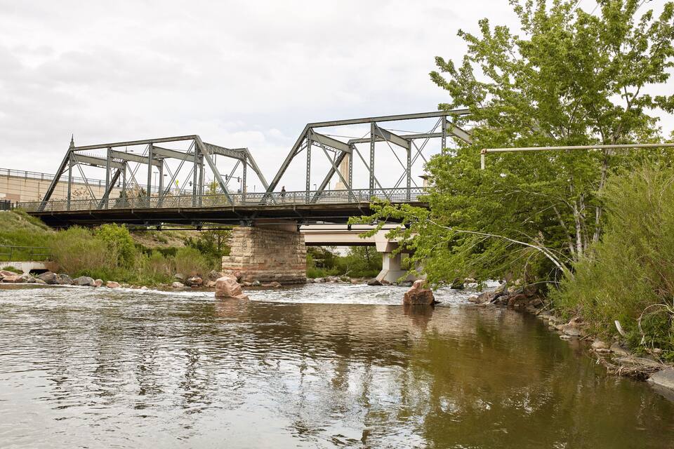Un puente de acero sobre un río, rodeado de vegetación.