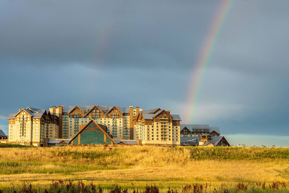 A large hotel complex with a prominent rainbow in the background.