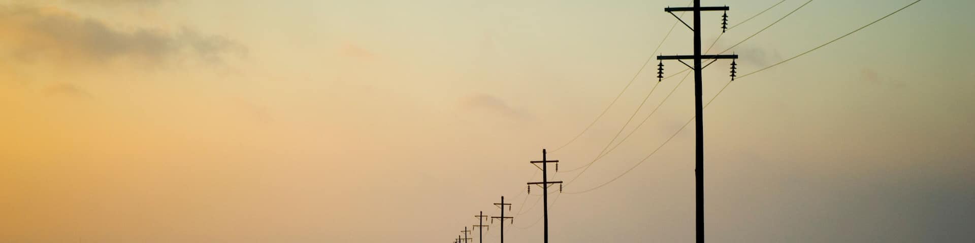 A snow-covered road with utility poles and power lines extending into the distance.