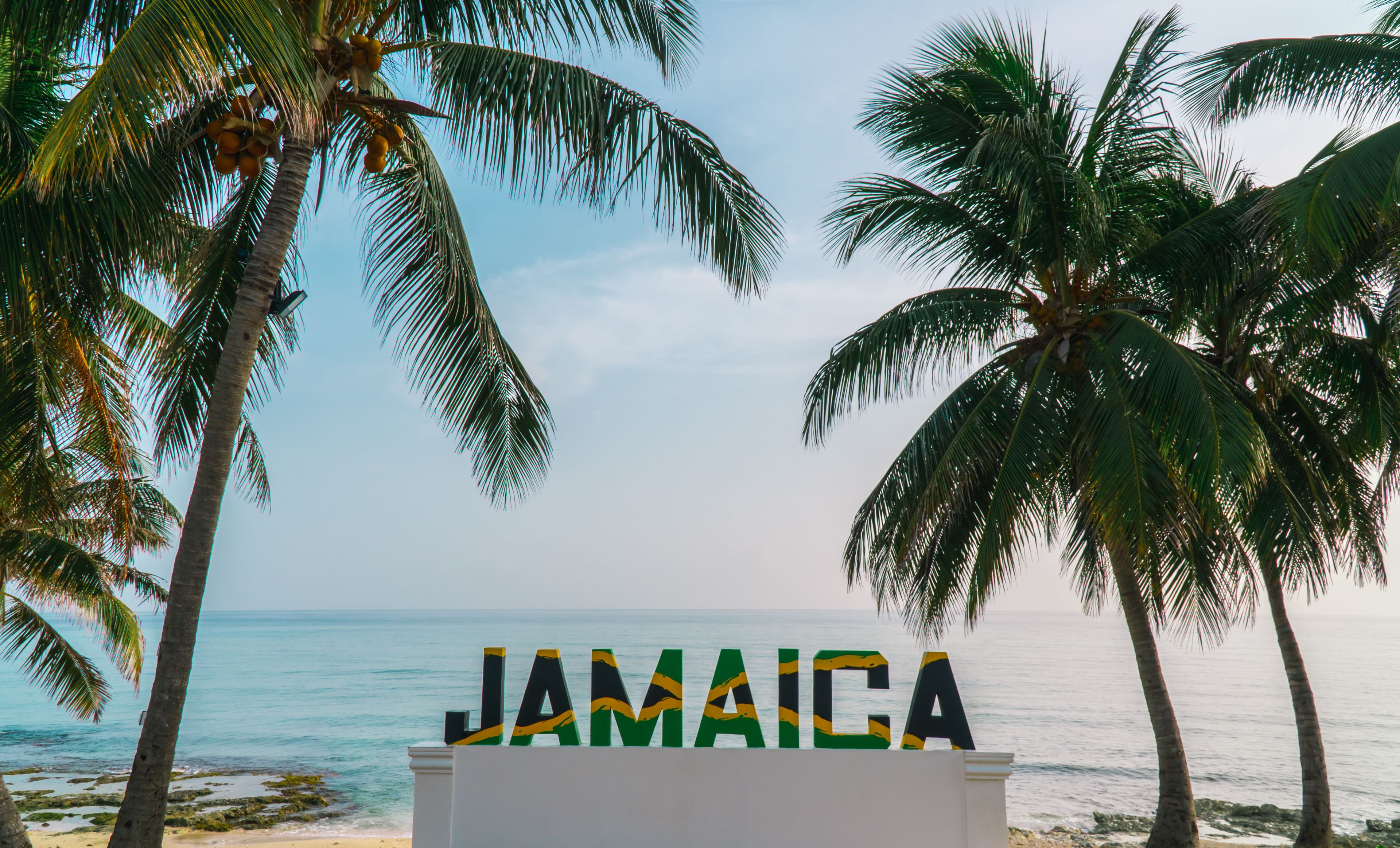 Una playa con palmeras y la palabra 'JAMAICA' al frente.
