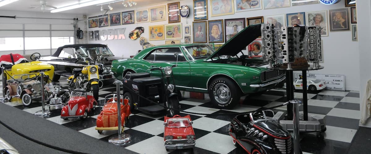 A classic car showroom with vintage cars, memorabilia, and a check for $10,000.