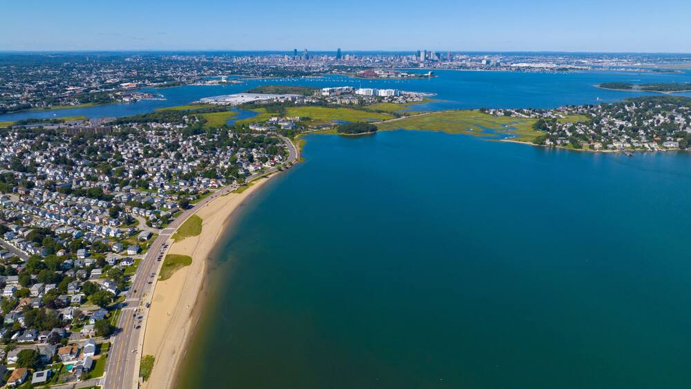 Wollaston Beach aerial view and Quincy Shore Drive next to the beach in Quincy Bay with Boston modern skyline at the background in Wollaston, city of Quincy, Massachusetts MA, USA.