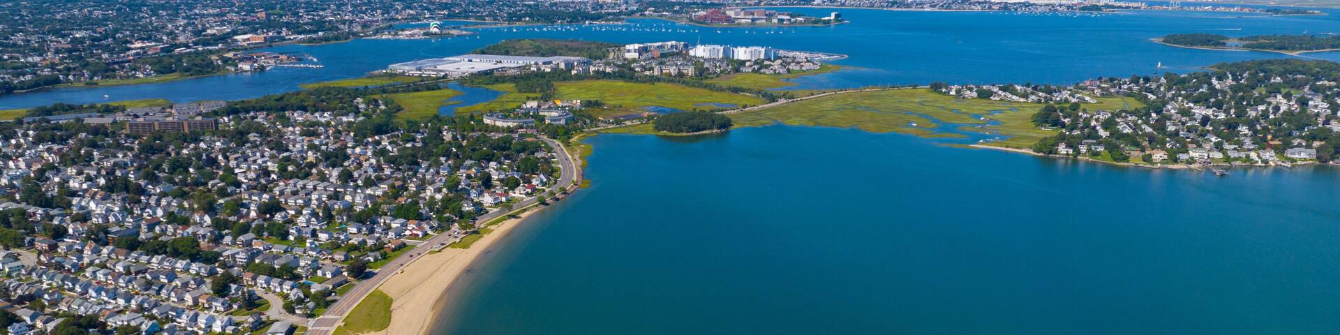 Wollaston Beach aerial view and Quincy Shore Drive next to the beach in Quincy Bay with Boston modern skyline at the background in Wollaston, city of Quincy, Massachusetts MA, USA.