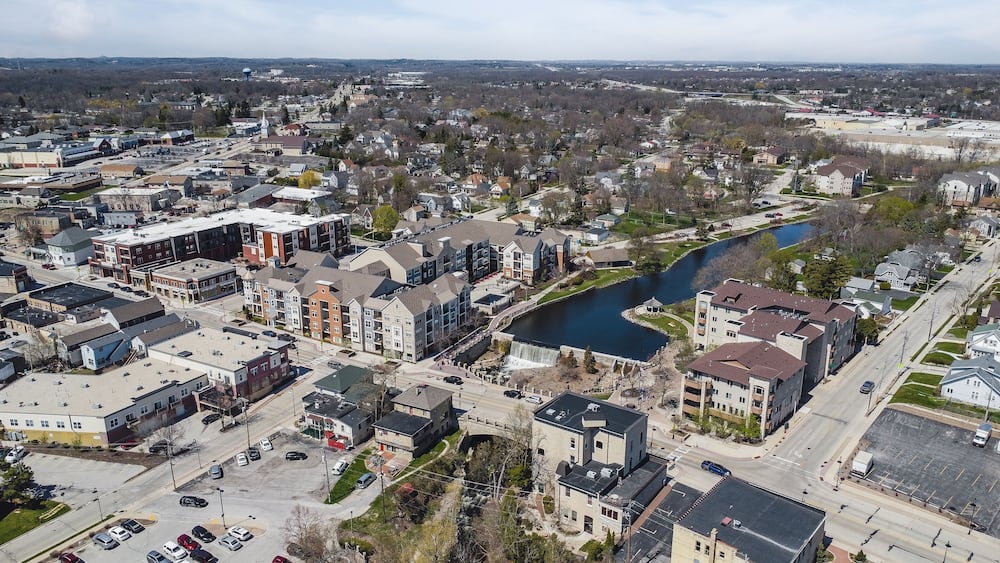 An aerial view of a town with a river, buildings, and a bridge.