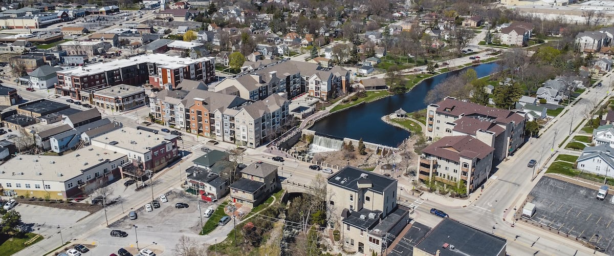 An aerial view of a town with a river, buildings, and a bridge.