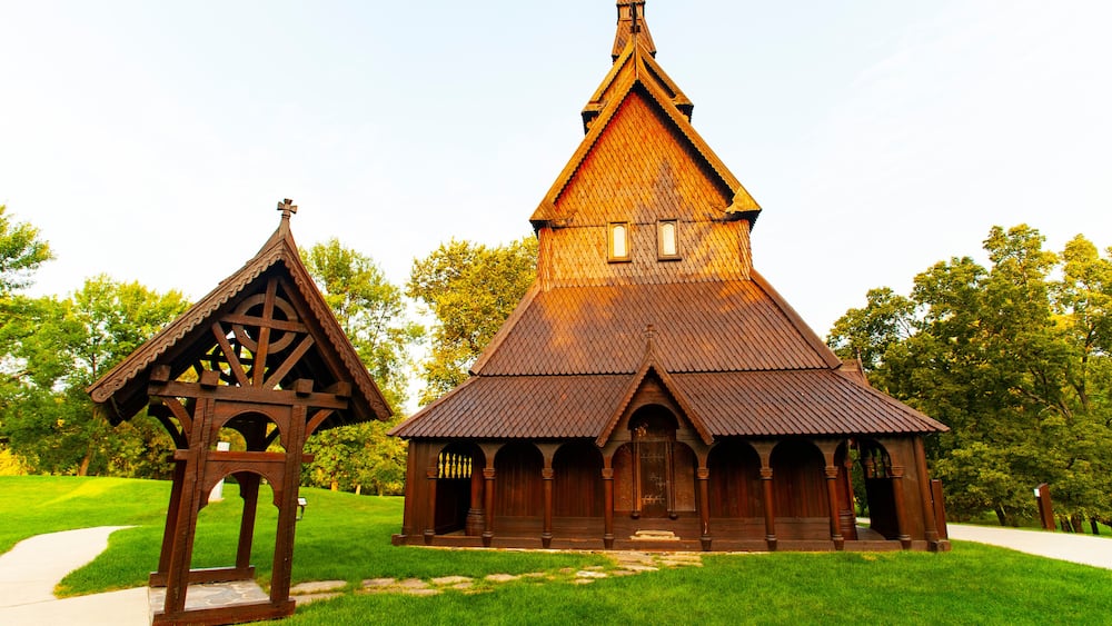 A wooden church with a steep gable roof and a smaller adjacent structure with a triangular roof.