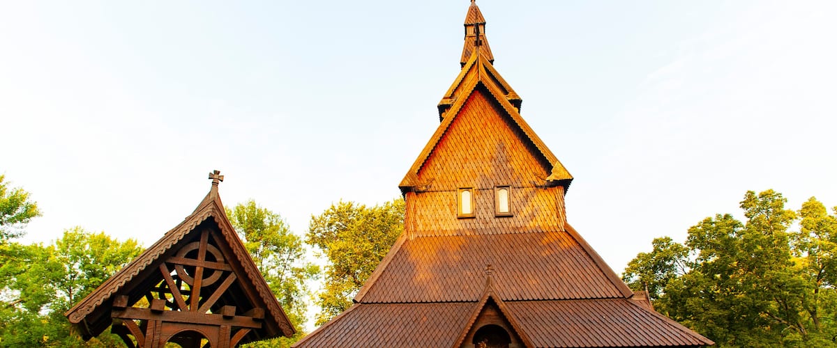 A wooden church with a steep gable roof and a smaller adjacent structure with a triangular roof.