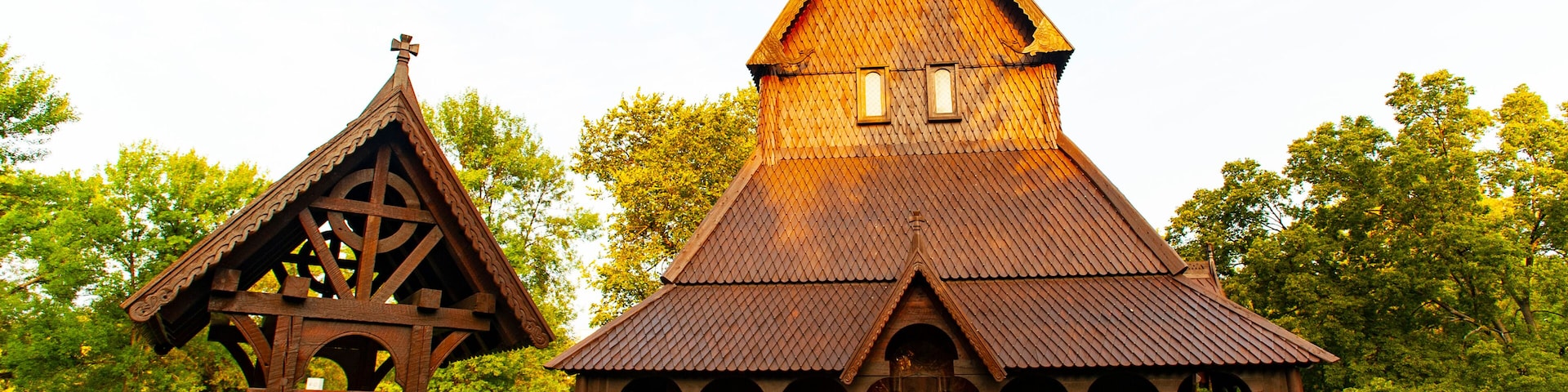 A wooden church with a steep gable roof and a smaller adjacent structure with a triangular roof.
