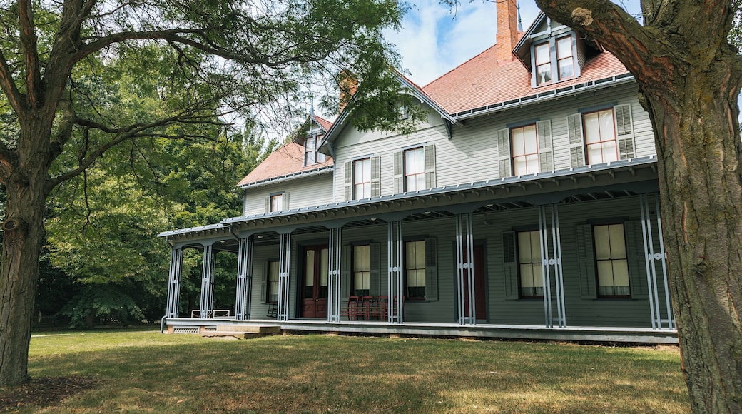 A large, two-story house with a porch, surrounded by trees and a well-maintained lawn.
