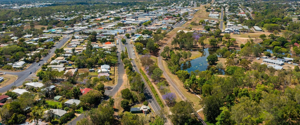 An aerial view of a town with a river, roads, and scattered buildings.