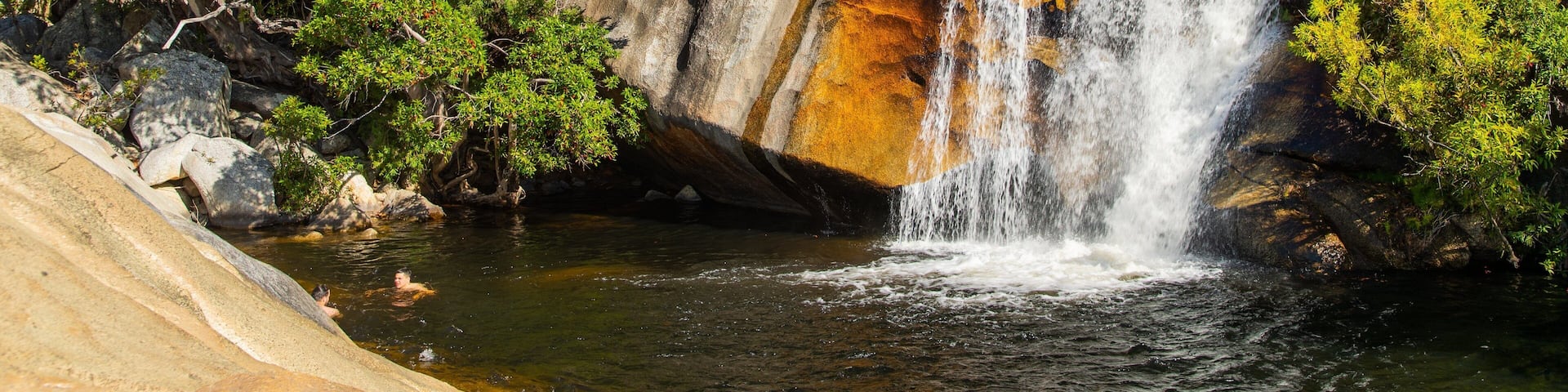 A waterfall cascading over rocks surrounded by lush greenery.