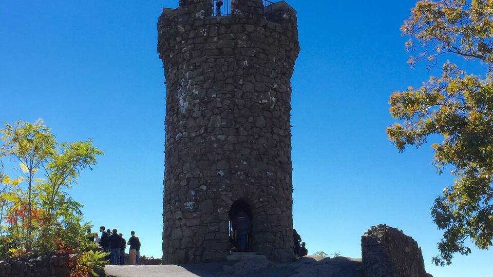 A stone tower with a small entrance, surrounded by grass and rocks.