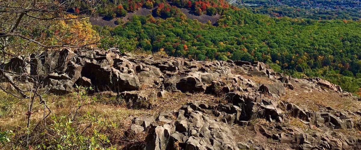 A mountainous landscape with rocky outcrops and autumn-colored trees.