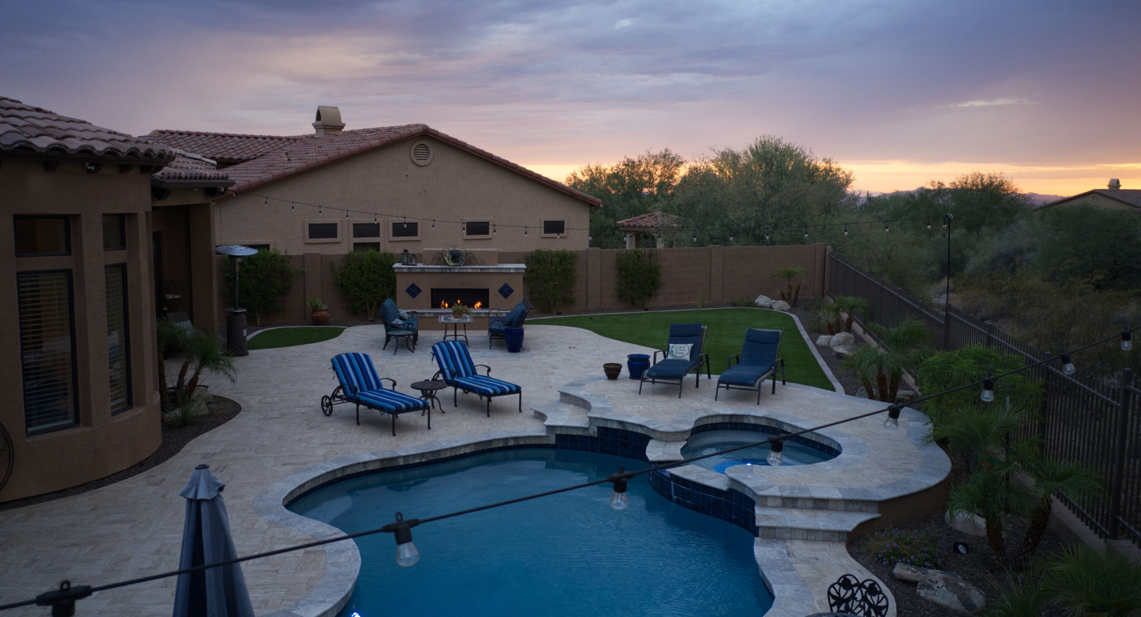 A backyard with a swimming pool, lounge chairs, and a patio area.