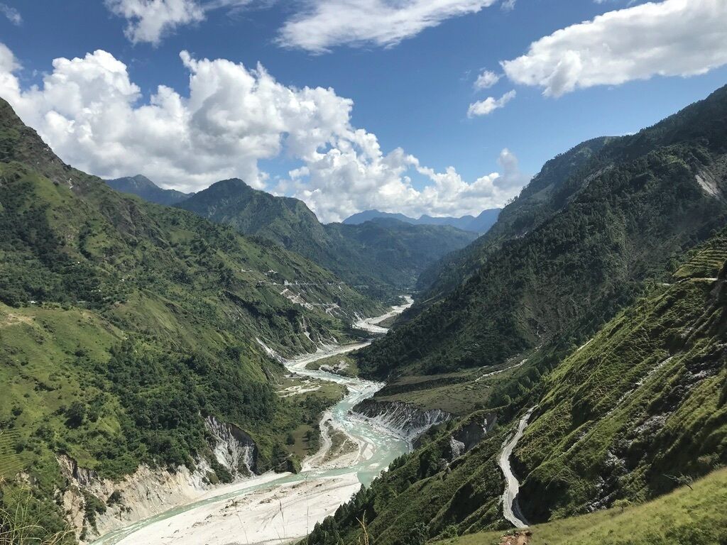 A river winding through a mountainous valley with lush greenery and a clear blue sky.