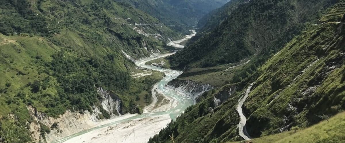 A river winding through a mountainous valley with lush greenery and a clear blue sky.