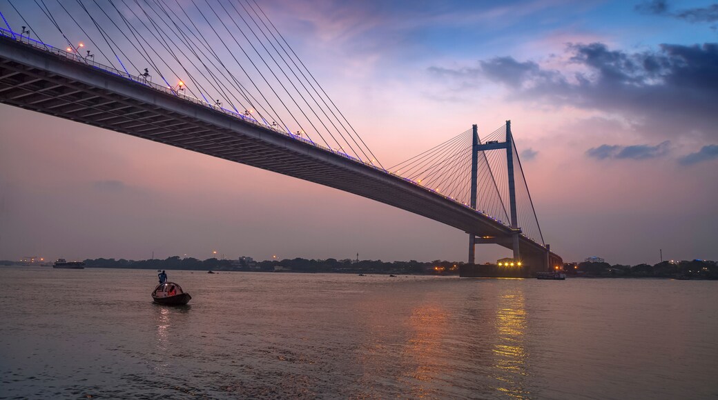 Vidyasagar Seu (bridge) at twilight with a wooden boat on the river. The cable bridge connects Kolkata with Howrah district.