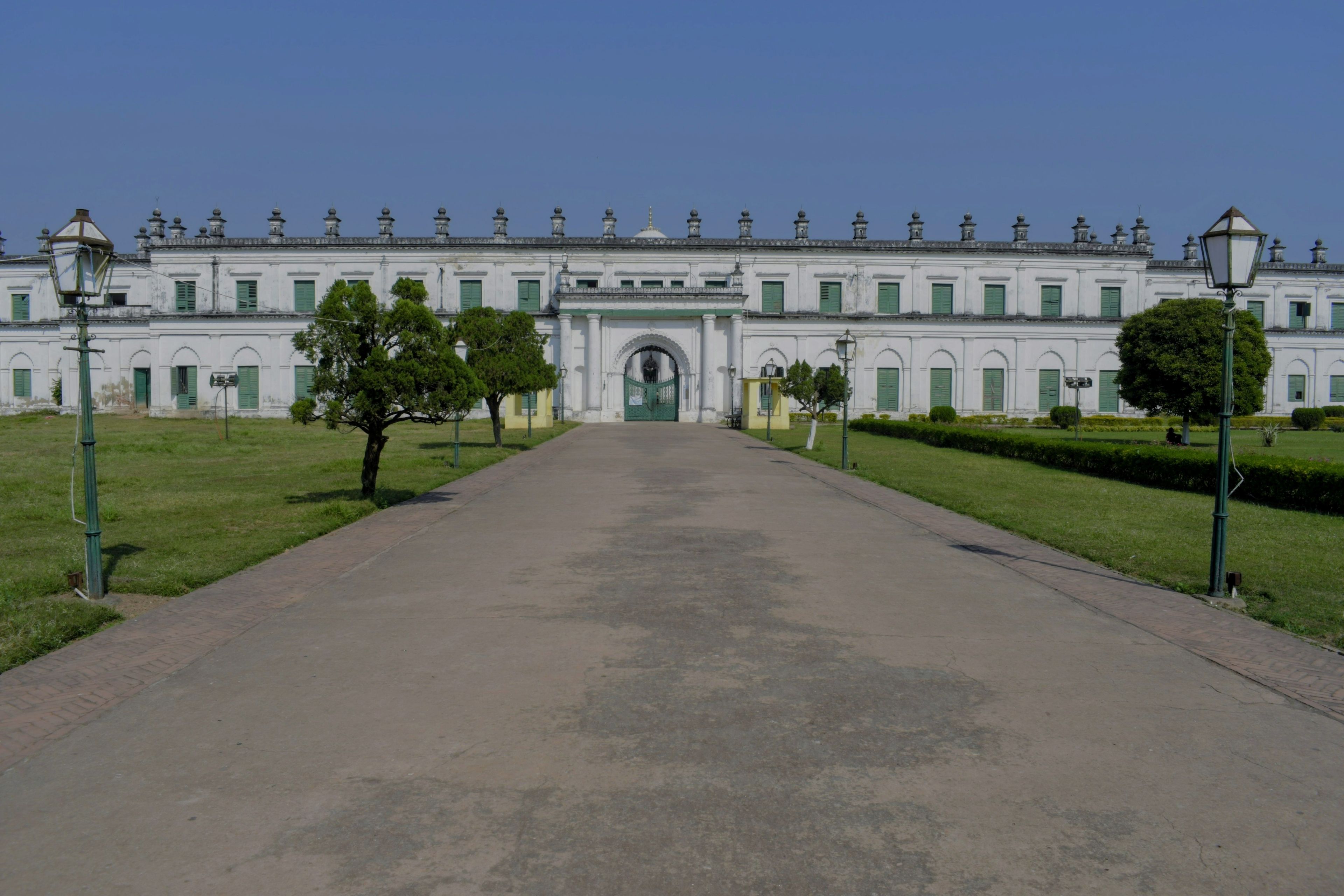 A large white building with a central entrance, surrounded by well-maintained lawns and trees.