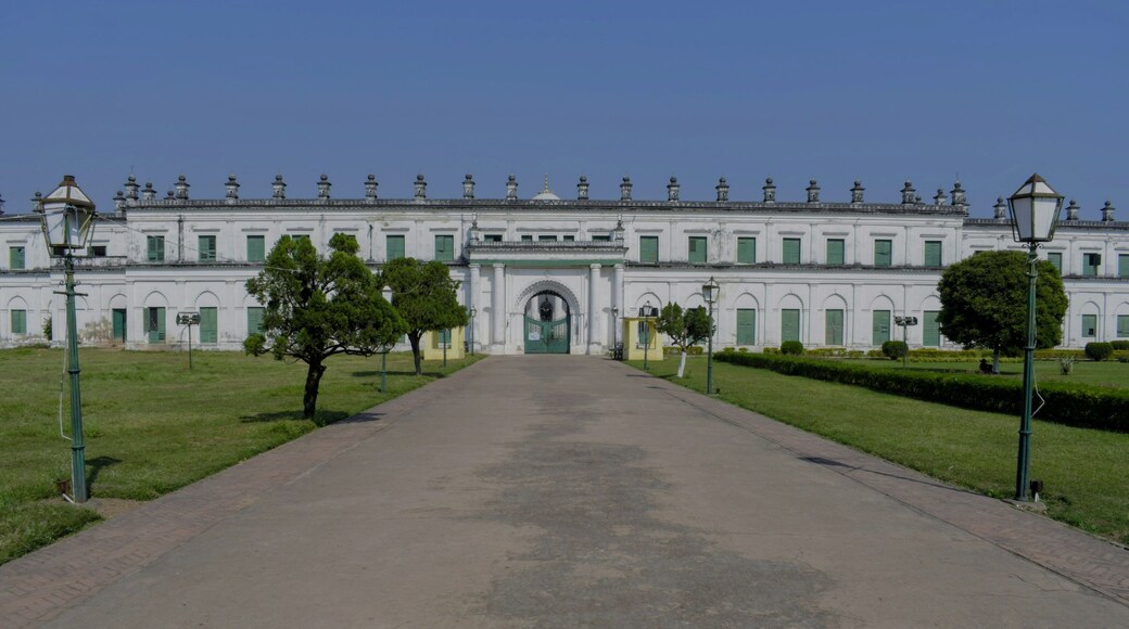 A large white building with a central entrance, surrounded by well-maintained lawns and trees.
