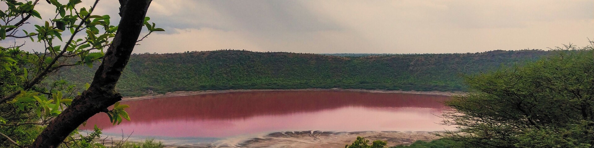 Ein großer See, umgeben von grünen Hügeln und Bäumen.