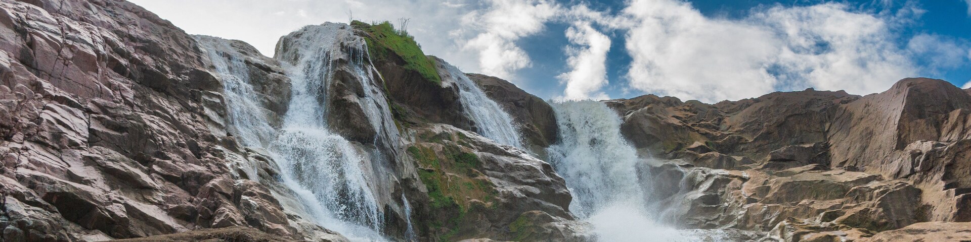 Waterfalls with blue sky, sunshine and clouds in a wide frame