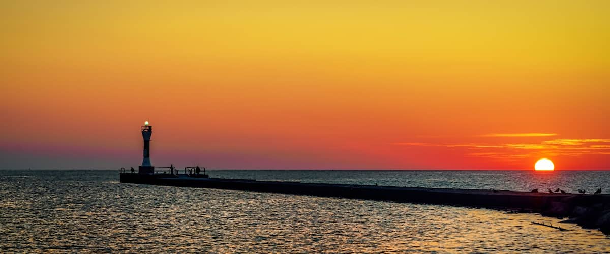 A lighthouse at sunset by the sea.
