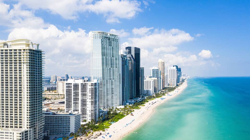 A coastal cityscape with high-rise buildings and a beach.