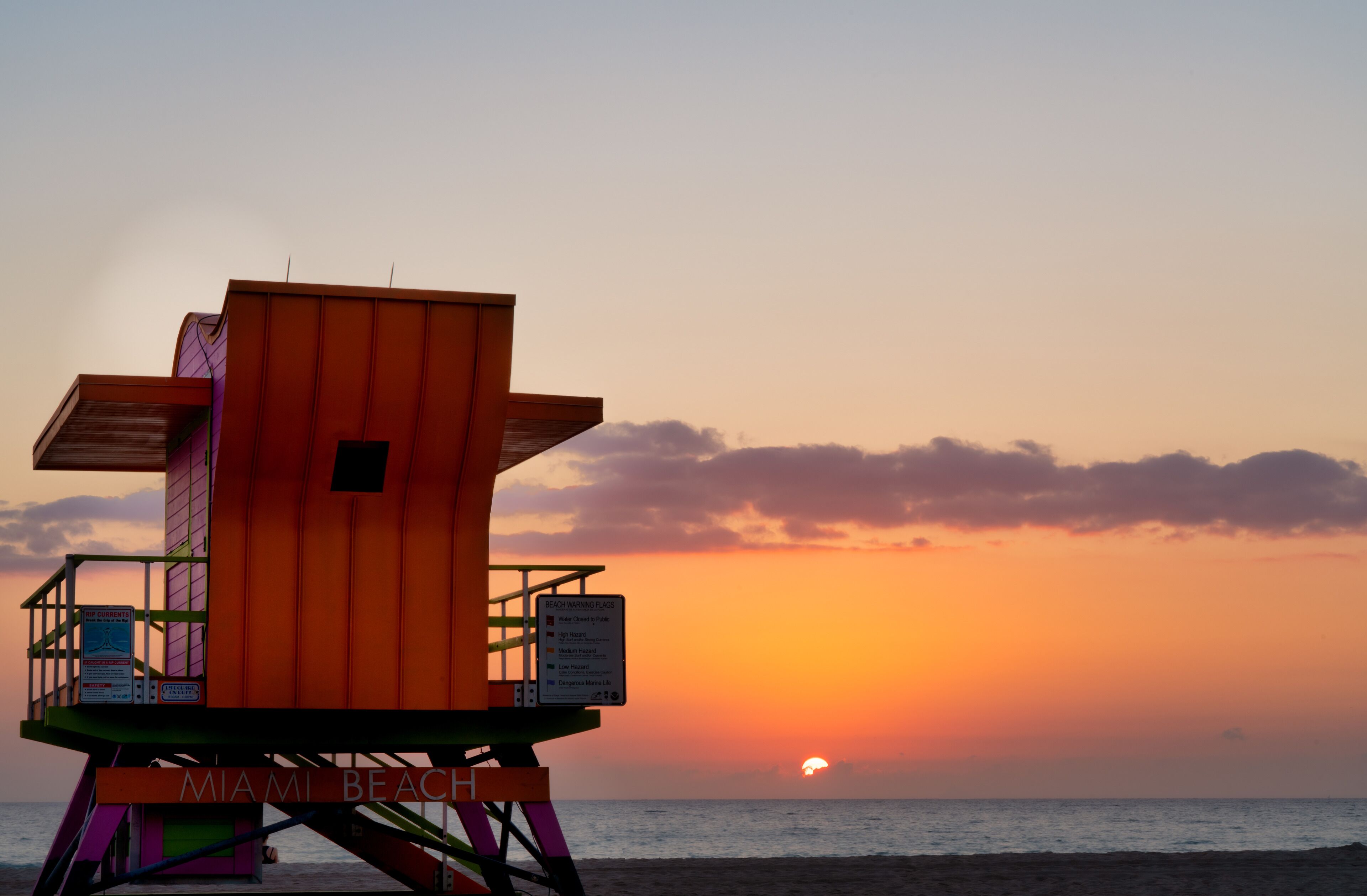 Un vigila-plats a la platja de Miami amb el sol ponent de fons.