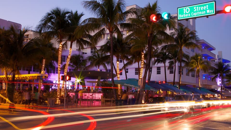 A street with palm trees, a building, and a traffic light.