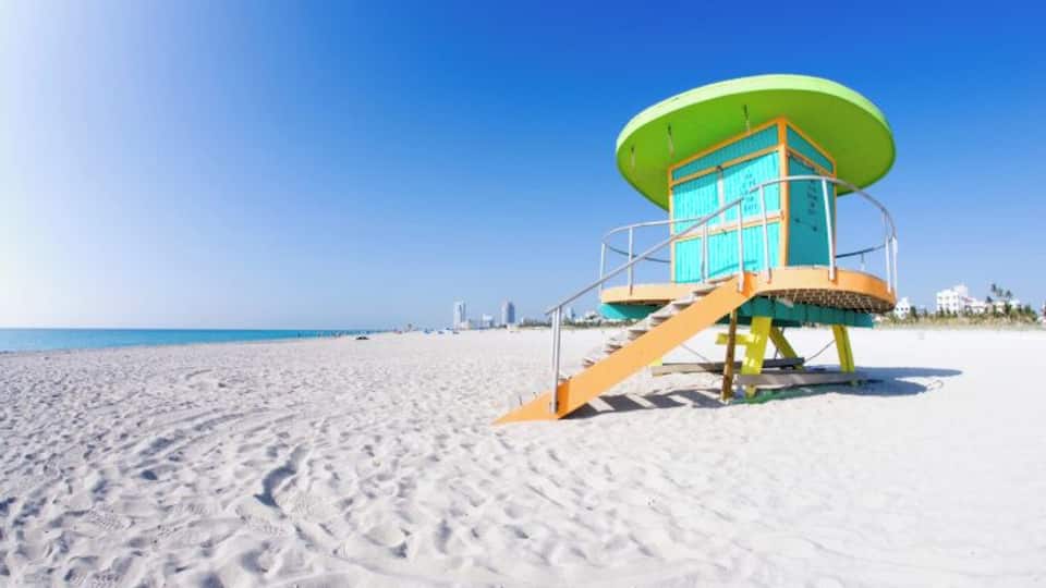 A lifeguard tower on a sandy beach with a clear blue sky.