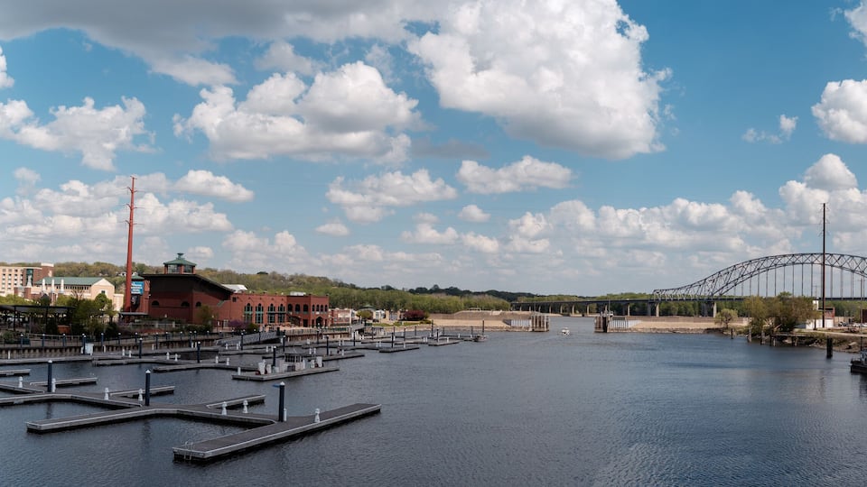 A river with docks, a bridge, and buildings in the background.