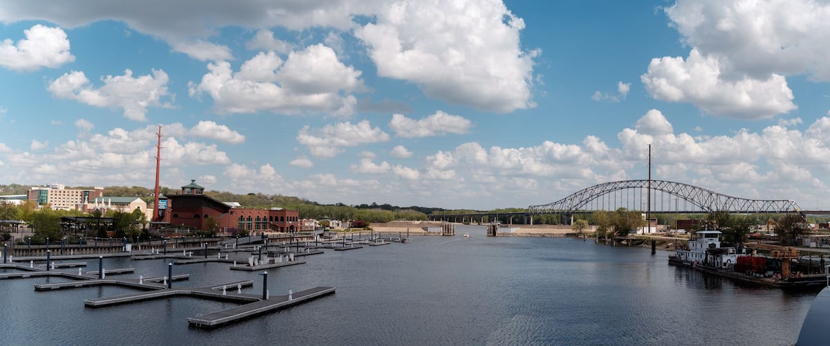 A river with docks, a bridge, and buildings in the background.