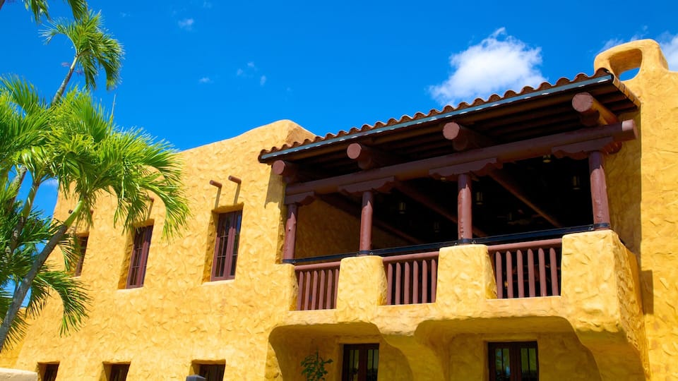 A yellow stucco building with a balcony and palm trees.