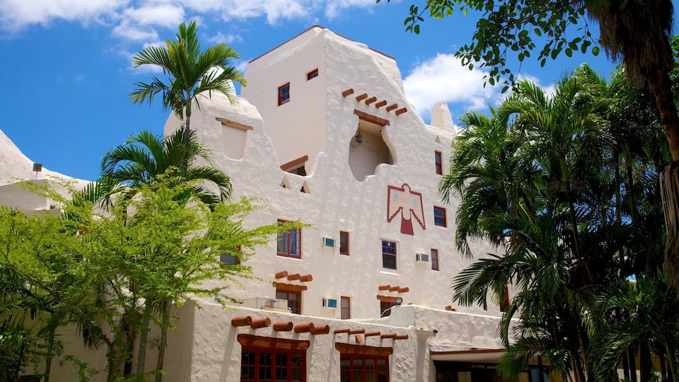 A white building with red accents and palm trees.