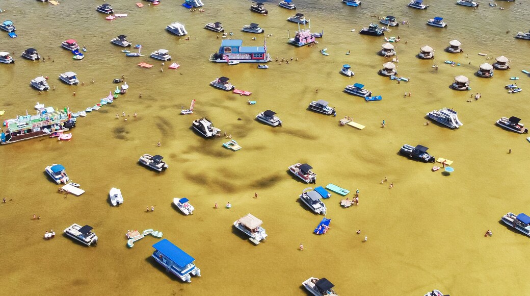 Panorama view crowd of people at Crab Island, Destin, Florida at low tide brown brackish water, busy pontoons, jet skis, paddleboards, swimming, wading at shallow water