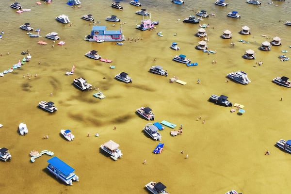 Panorama view crowd of people at Crab Island, Destin, Florida at low tide brown brackish water, busy pontoons, jet skis, paddleboards, swimming, wading at shallow water