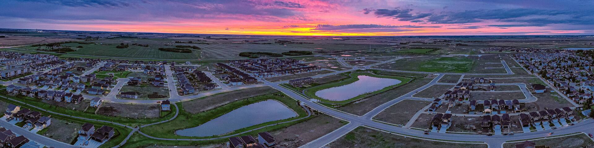 A suburban area with multiple housing developments, roads, and water bodies.
