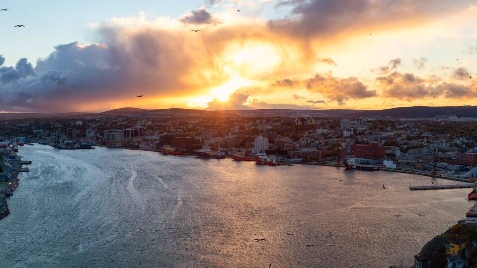 Aerial panoramic view of a modern cityscape on the Atlantic Ocean Coast during a dramatic sunset. Taken in St. John's, Newfoundland and Labrador, Canada.