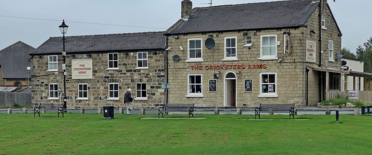 A stone building with a sign reading "The Cricketers Arms".