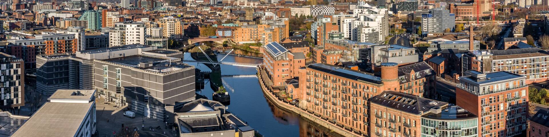 A cityscape with a river, modern buildings, and a bridge.