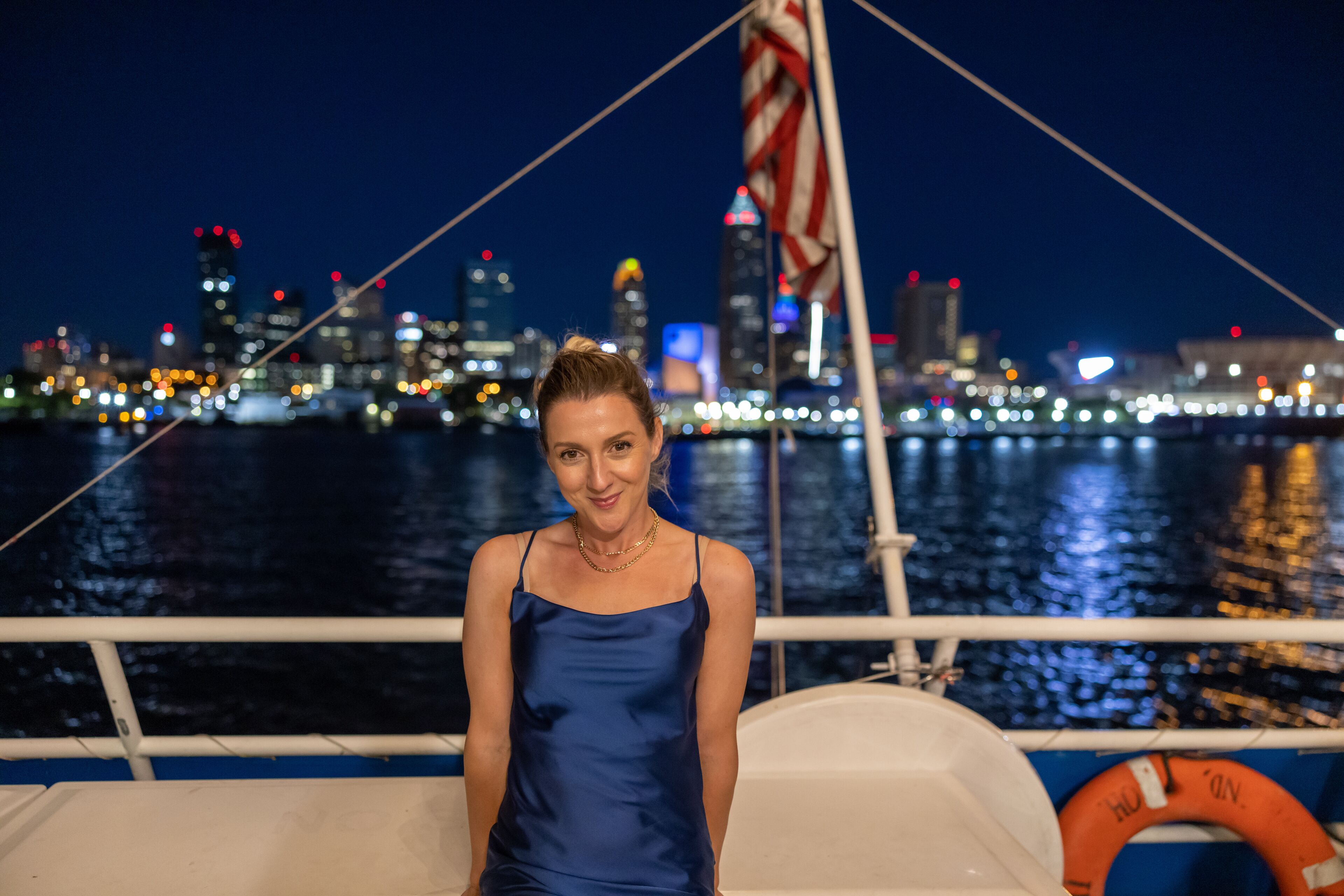 Young woman on a boat with illuminated Cleveland skyline in the background. 