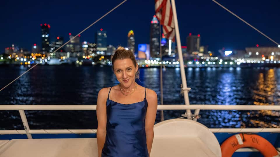 A person on a boat with a city skyline in the background.