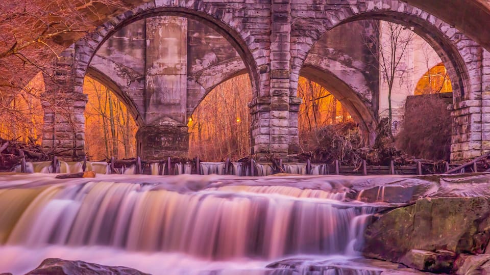 A stone bridge with multiple arches over a flowing river.
