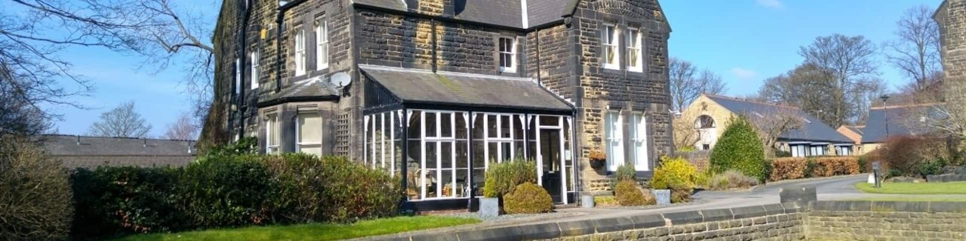 A large stone house with a steep roof and a glass conservatory.
