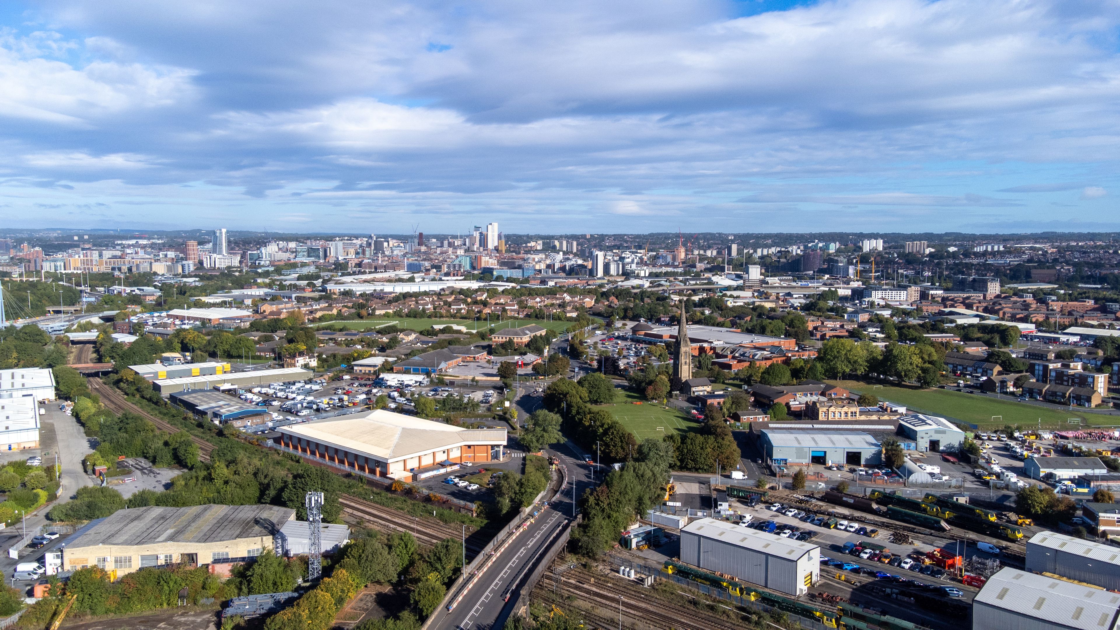 A cityscape with a mix of residential and industrial areas, a prominent church spire, and a railway line.