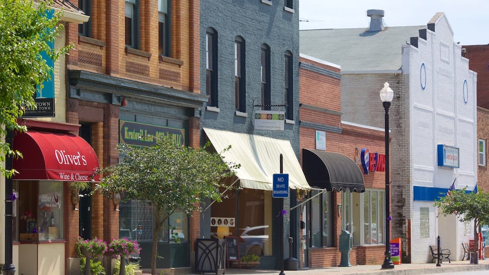A street lined with various shops, including a wine and cheese store, a restaurant, and a coffee shop.