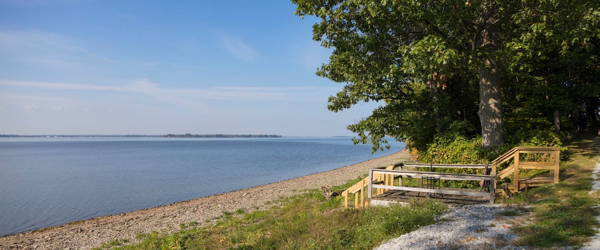 A lakeside scene with a wooden dock, a blue canoe, and a rocky shoreline.